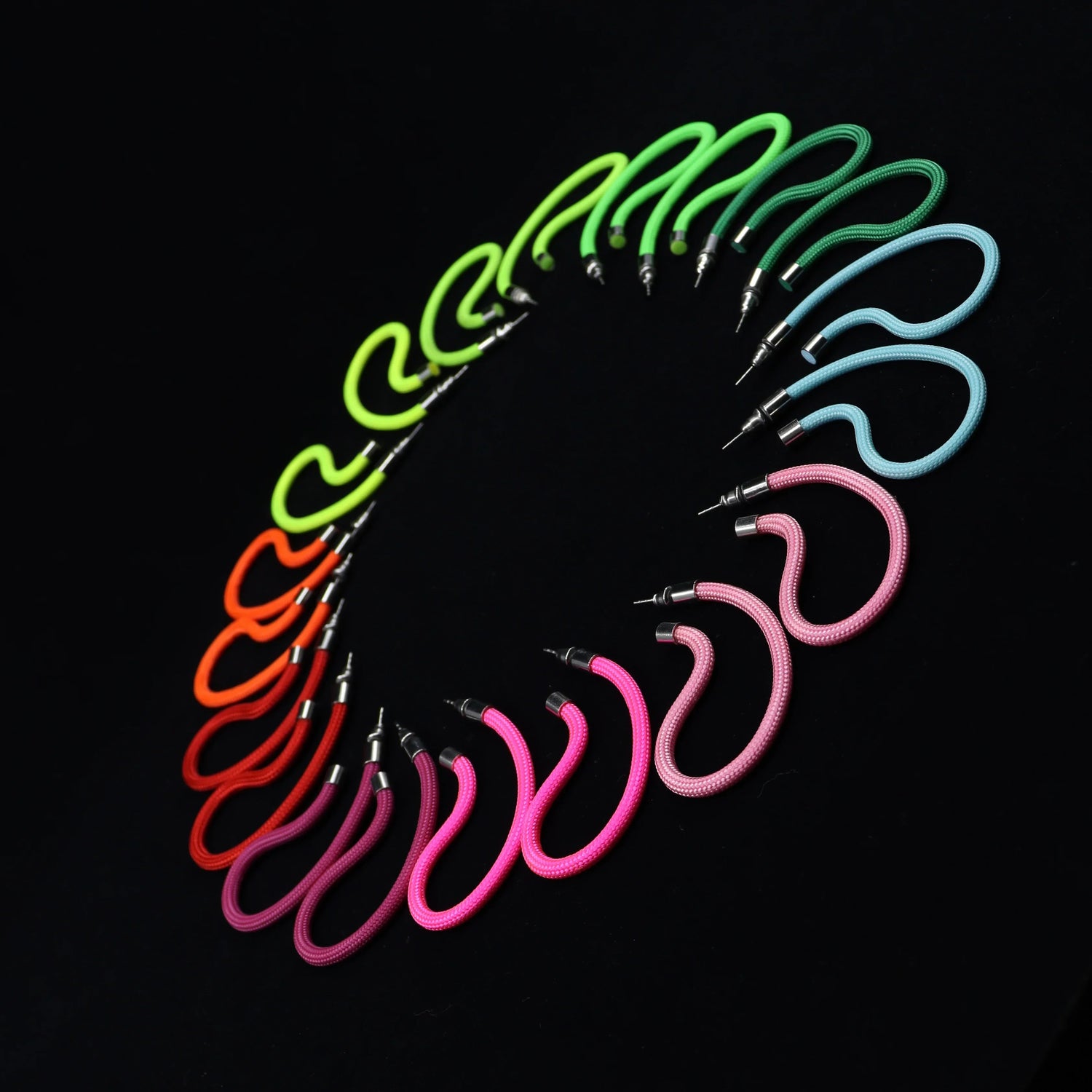 Colorful modular hoop earrings arranged in a semi-circle on black background, showcasing vibrant wearable art