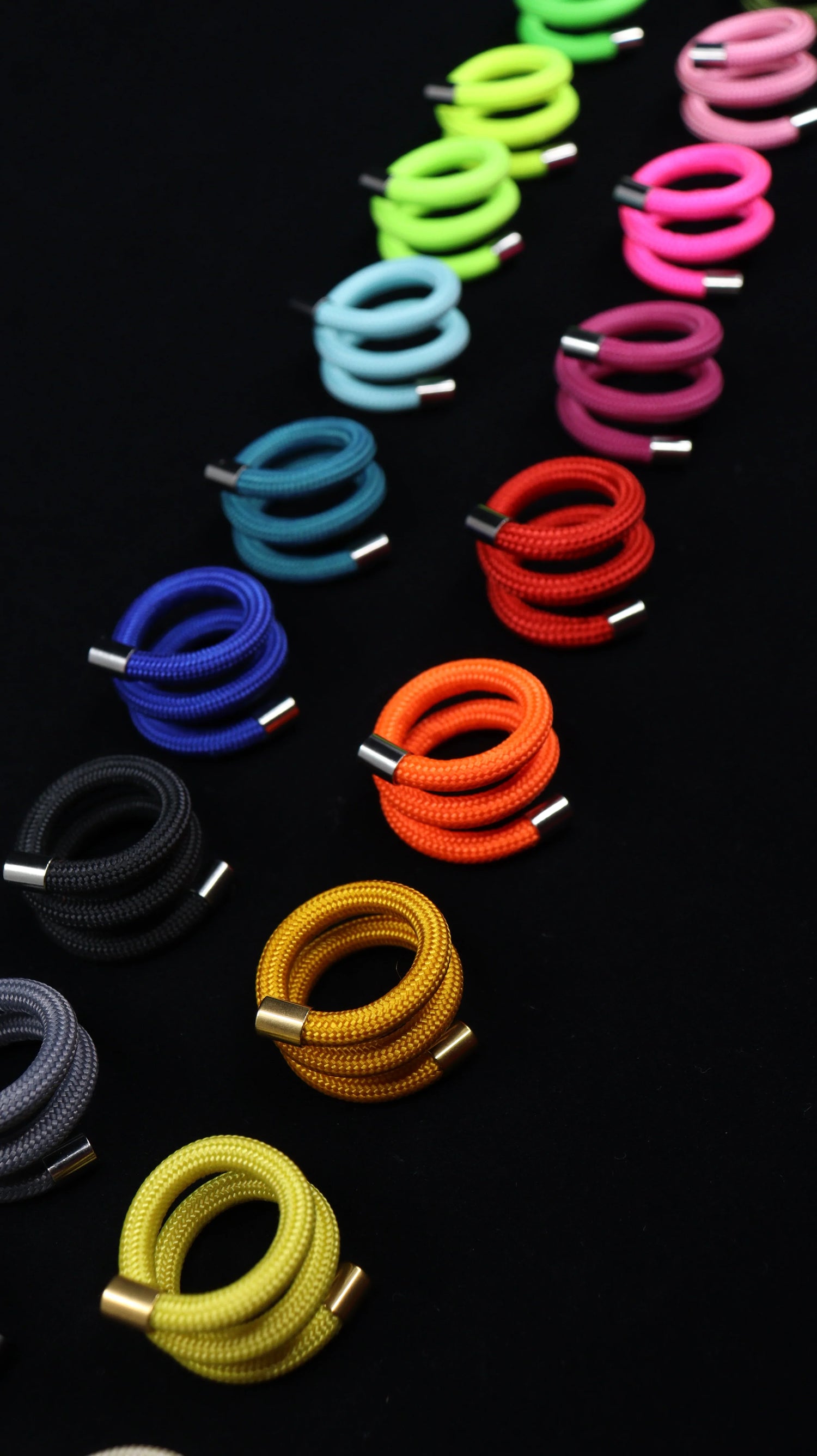 Colorful coiled modular rings with metal tips from FuturisNow Linea collection on black background