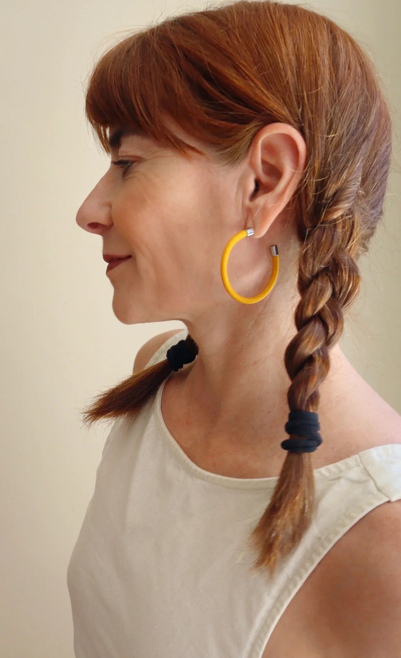 Woman with braided red hair wearing colorful yellow hoop earring from FuturisNow's Linea collection
