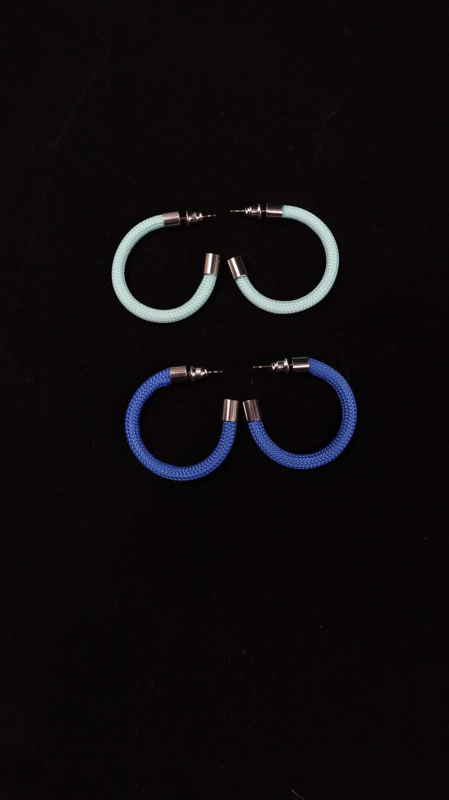 Two pairs of colorful hoop earrings from FuturisNow Linea collection, one light turquoise and one royal blue on black