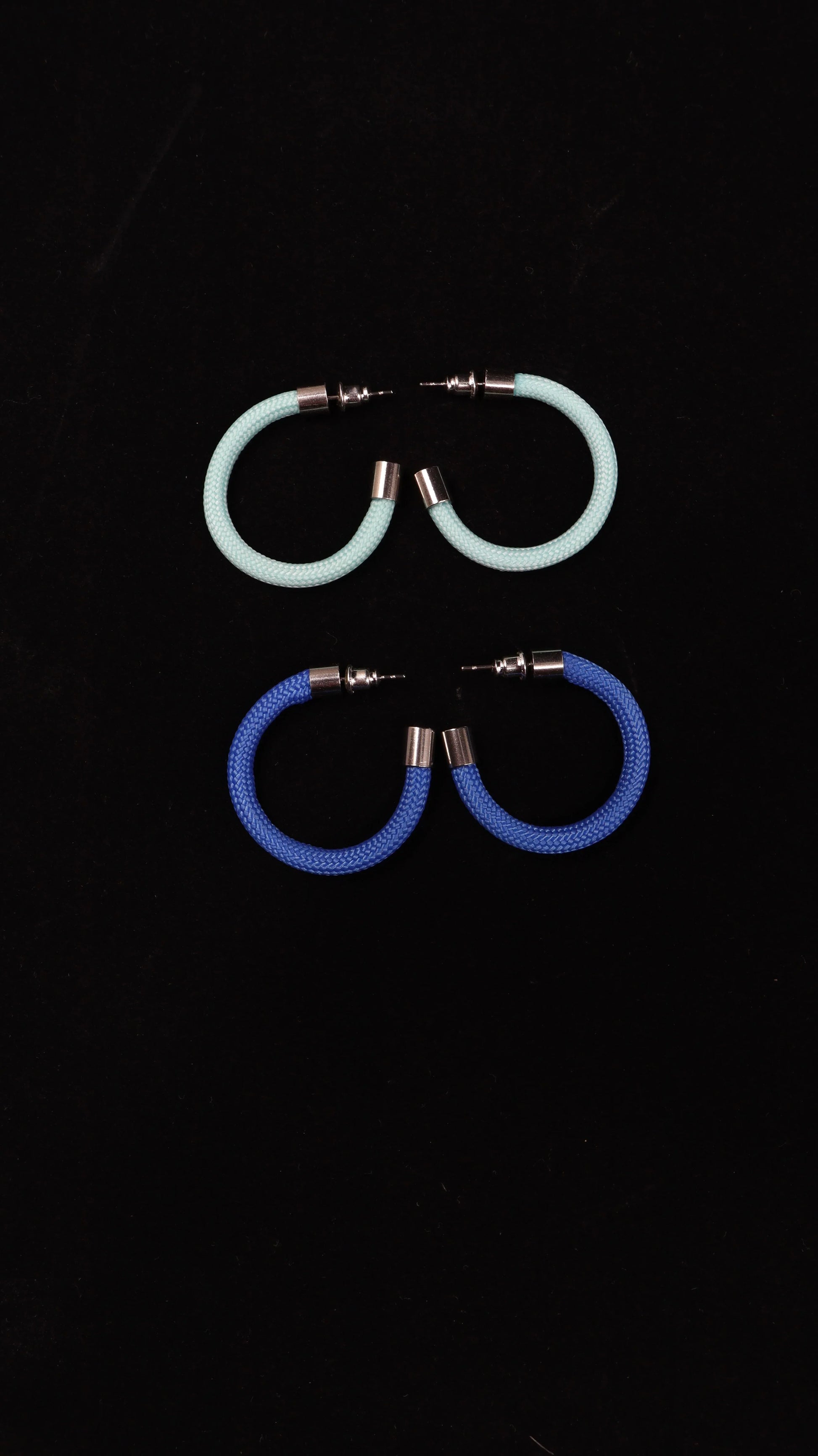 Two pairs of colorful hoop earrings from FuturisNow Linea collection, one light turquoise and one royal blue on black