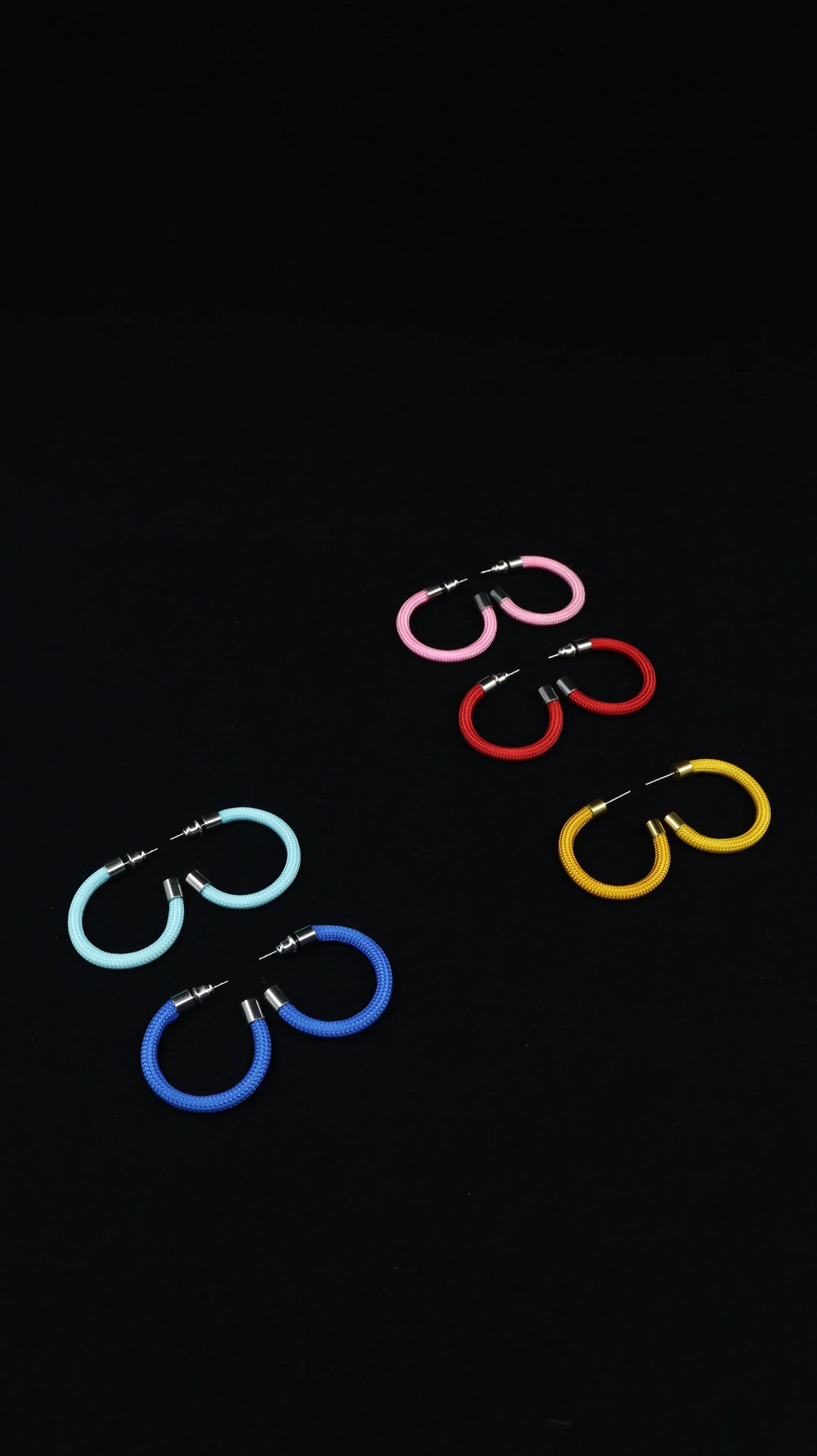 Colorful hoop earrings in pink, red, yellow, blue, and light blue on a black background