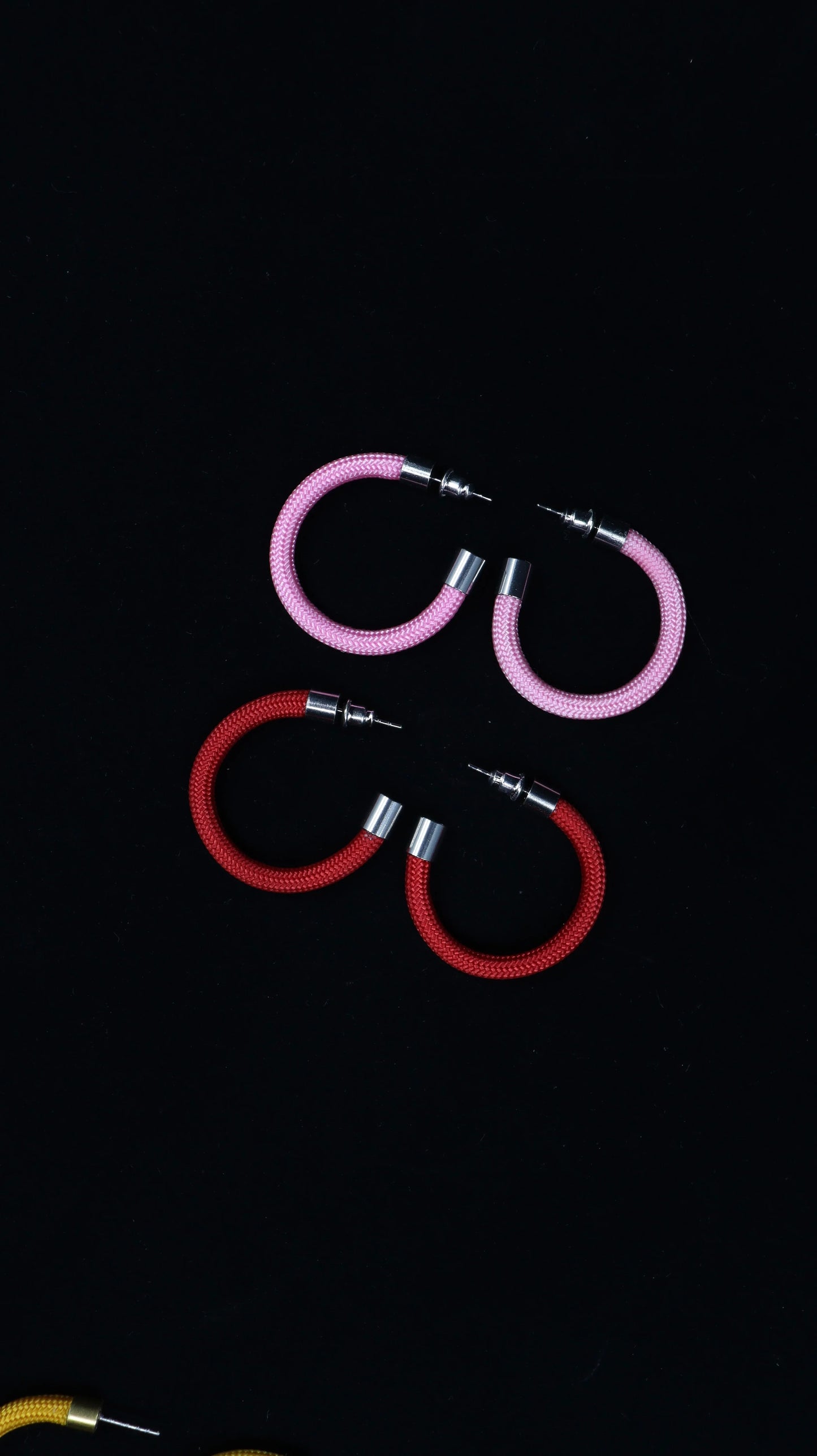 Pair of pink and pair of red modular hoop earrings with silver accents on black background